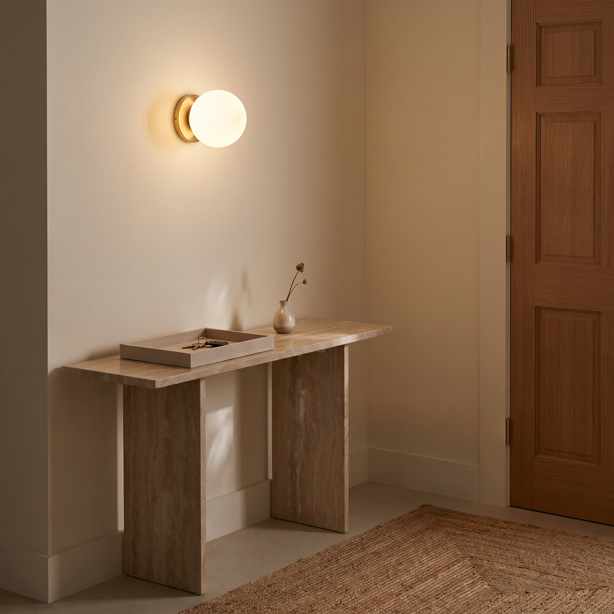 Orbelle globe sconce above a narrow stone entryway console
